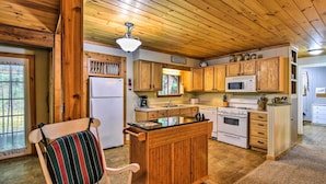 A cozy cabin kitchen with wooden cabinets, a central island, a refrigerator, a microwave, and a stove. - Robbinsville Cabin w/ Deck: 3 Mi to Fontana Lake! (Robbinsville)