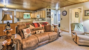A cozy living room with a leather sofa, a wooden coffee table, and a fireplace. - Robbinsville Cabin w/ Deck: 3 Mi to Fontana Lake! (Robbinsville)