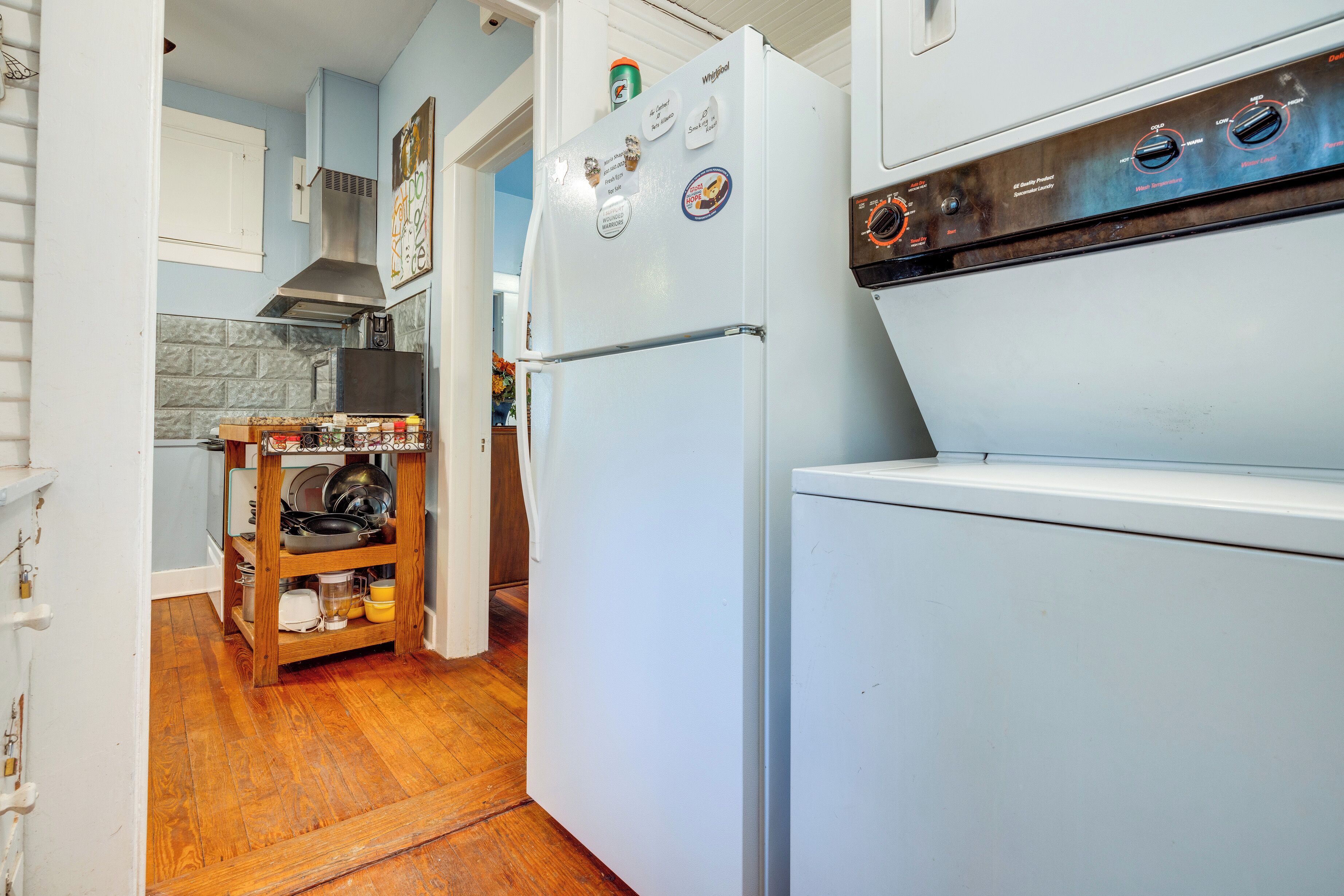 Una cocina con un refrigerador blanco, una repisa de madera con vajilla y un extractor de acero inoxidable.