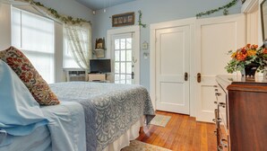 Une chambre à coucher avec un lit, une commode, un téléviseur et une porte.