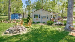 Eingeschossiges Haus mit Veranda, Terrasse und Feuerstelle im Garten.