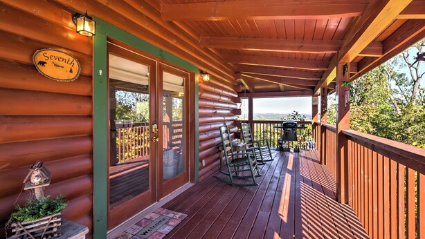 A wooden deck with a view of the landscape, a sign reading "Seventh Heaven," and a welcome mat.