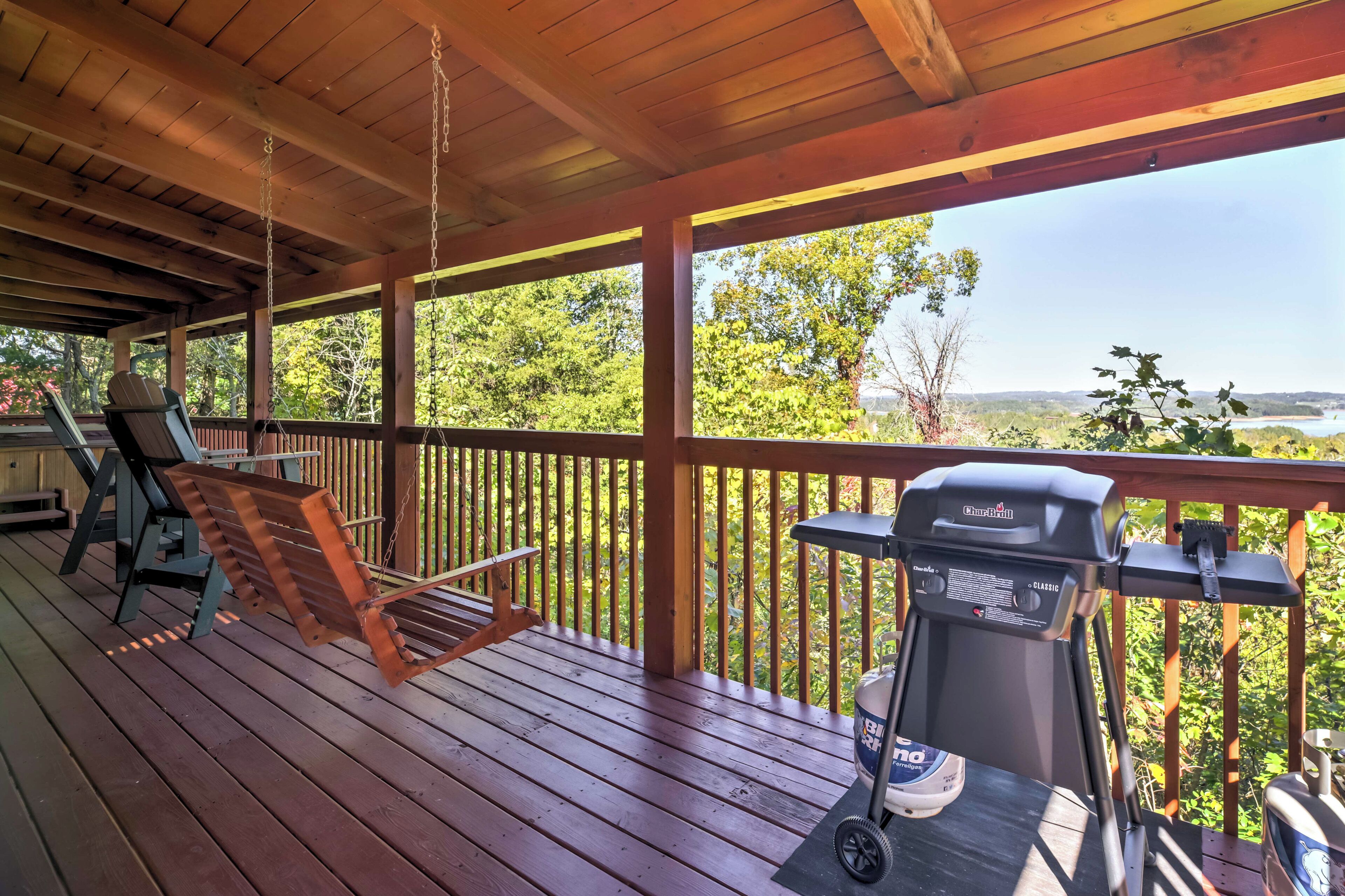 A wooden deck with a swing chair and a grill.