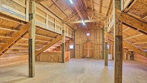 An attic space with wooden beams, a sloped ceiling, and a central window.