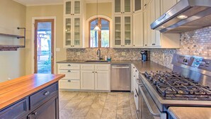 A kitchen with white cabinetry, a stainless steel range, and a brick backsplash.