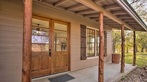 A wooden front door with glass panels, a porch with wooden posts, and a concrete walkway leading to the door.