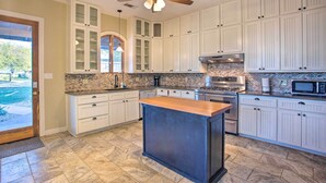A kitchen with white cabinets, a central island, a ceiling fan, and a brick backsplash.
