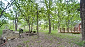 A campsite with picnic tables, a fire pit, and a wooden cabin. - Cozy Fredericksburg Cabin With Shared Hot Tub! (Fredericksburg)