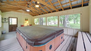A hot tub in a room with wooden beams, large windows, and a view of trees. - Cozy Fredericksburg Cabin With Shared Hot Tub! (Fredericksburg)