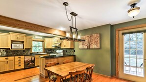 A spacious kitchen with wooden cabinets, a large island, and a dining area with a wooden table and chairs. - Black Mountain Cabin w/ Screened Porch + Views! (Black Mountain)