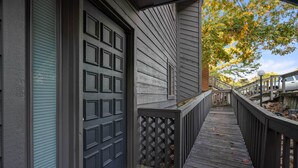 A wooden deck with a metal railing, a garage door, and a small porch area. - Hot Springs Vacation Rental w/ Game Room! (Hot Springs)