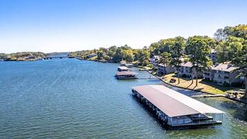 A waterfront property with a dock, a covered boat launch, and a building with a flat roof.