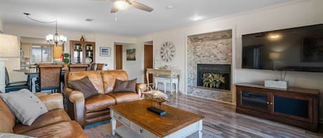A spacious living room with a leather sofa, a wooden coffee table, and a fireplace.