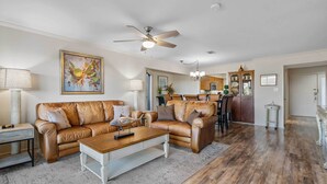 A spacious living room with a brown leather sofa, a wooden coffee table, and a ceiling fan. - Hot Springs Vacation Rental w/ Game Room! (Hot Springs)