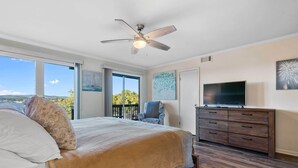 A bedroom with a large bed, a ceiling fan, a TV, and a balcony with a chair. - Hot Springs Vacation Rental w/ Game Room! (Hot Springs)