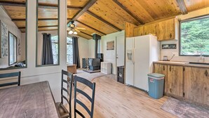 Interior de madera con comedor, cocina y ventana con vistas a árboles.