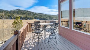 A wooden deck with outdoor furniture, a large window, and a view of a forested mountain. - Cripple Creek Retreat w/ Incredible Mtn Views! (Cripple Creek)