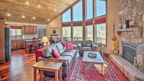 A spacious living room with a fireplace, leather furniture, and large windows. - Cripple Creek Retreat w/ Incredible Mtn Views! (Cripple Creek)