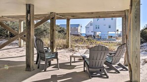 An outdoor seating area with wooden pergola, two Adirondack chairs, and a small table. - Gulf Shores Rental w/ Large Porch - Beach View! (Gulf Shores)