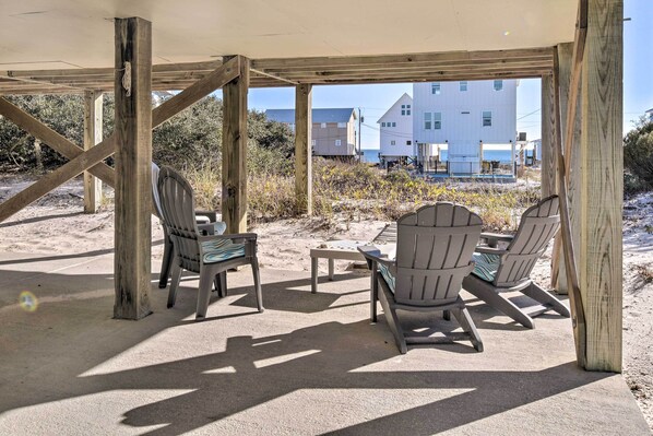 An outdoor seating area with wooden pergola, two Adirondack chairs, and a small table.