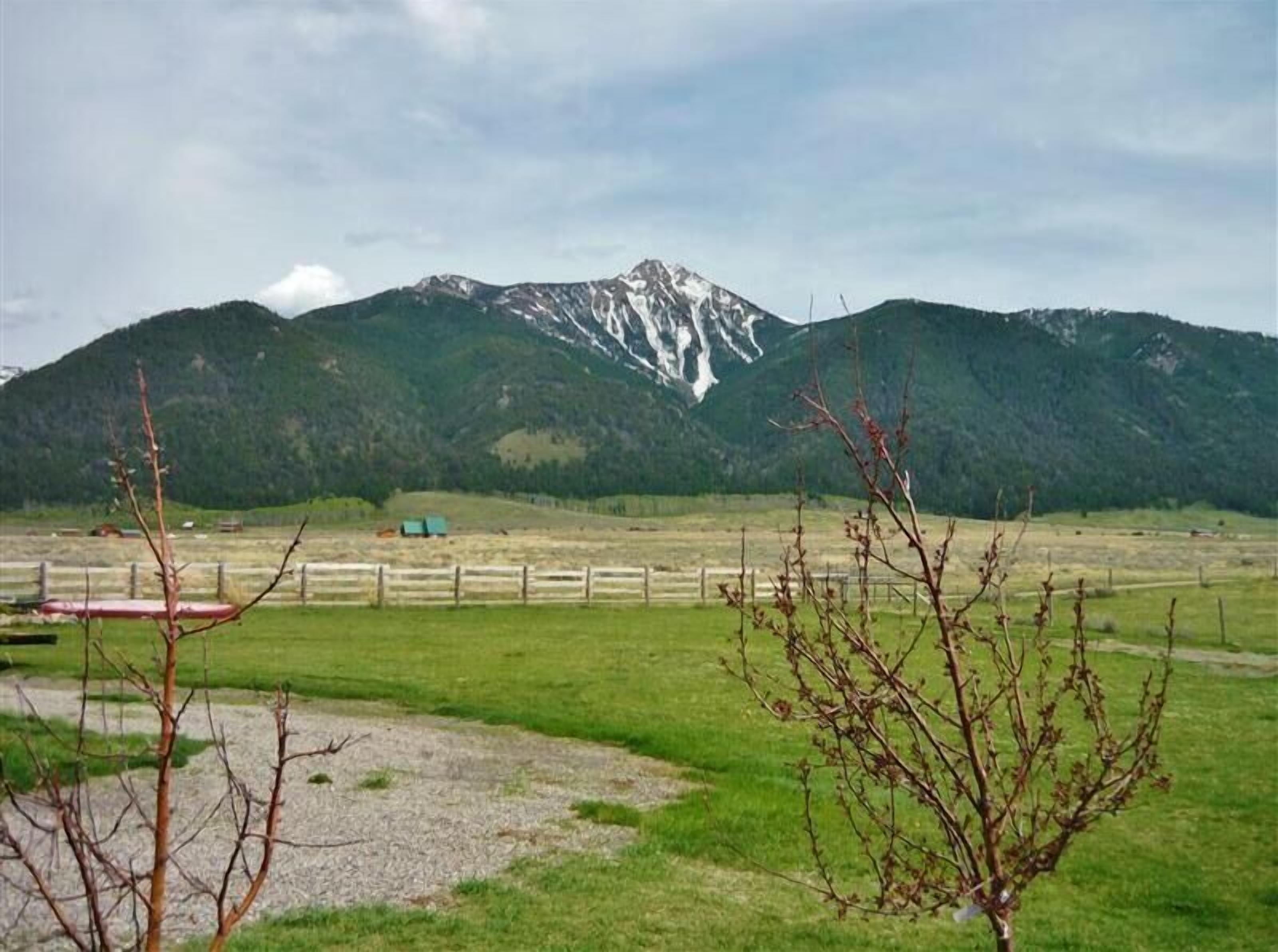 Eine gebirgige Landschaft mit einer grünen Wiese und einem Holzzaun.