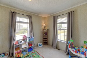 A child's playroom with a window, a bookshelf, a toy train, and a play mat. - Family Home + Fire Pit & Deck, 11 Miles to Beach! (Stella)