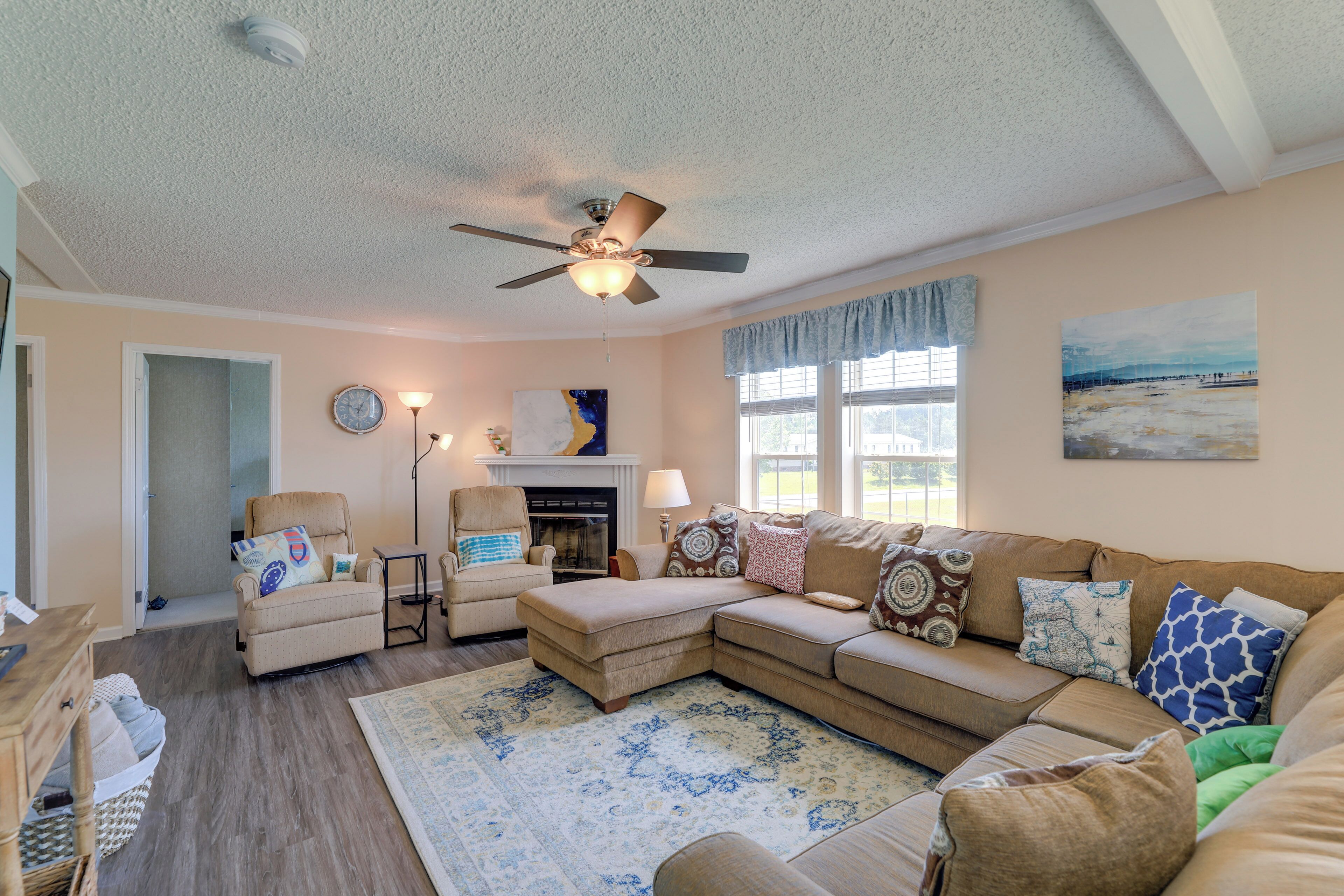 A living room with a sectional sofa, a chaise lounge, a fireplace, and a ceiling fan.