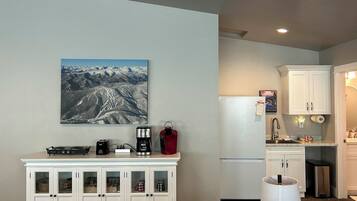 A compact kitchen with a refrigerator, a coffee maker, and a microwave on the counter.