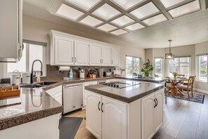 A modern kitchen with white cabinets, granite countertops, and a central island. - Waterfront Discovery Bay Home w/ Private Dock (Discovery Bay)