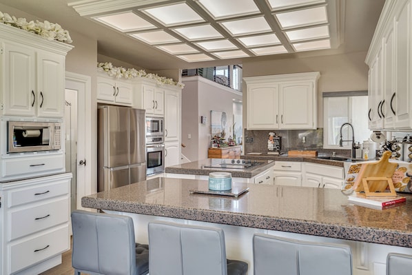 A modern kitchen with white cabinetry, stainless steel appliances, and a granite countertop.