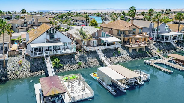 A coastal residential area with houses connected by walkways to a dock area with boats.