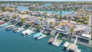 An aerial view of a coastal residential area with houses, docks, and boats.