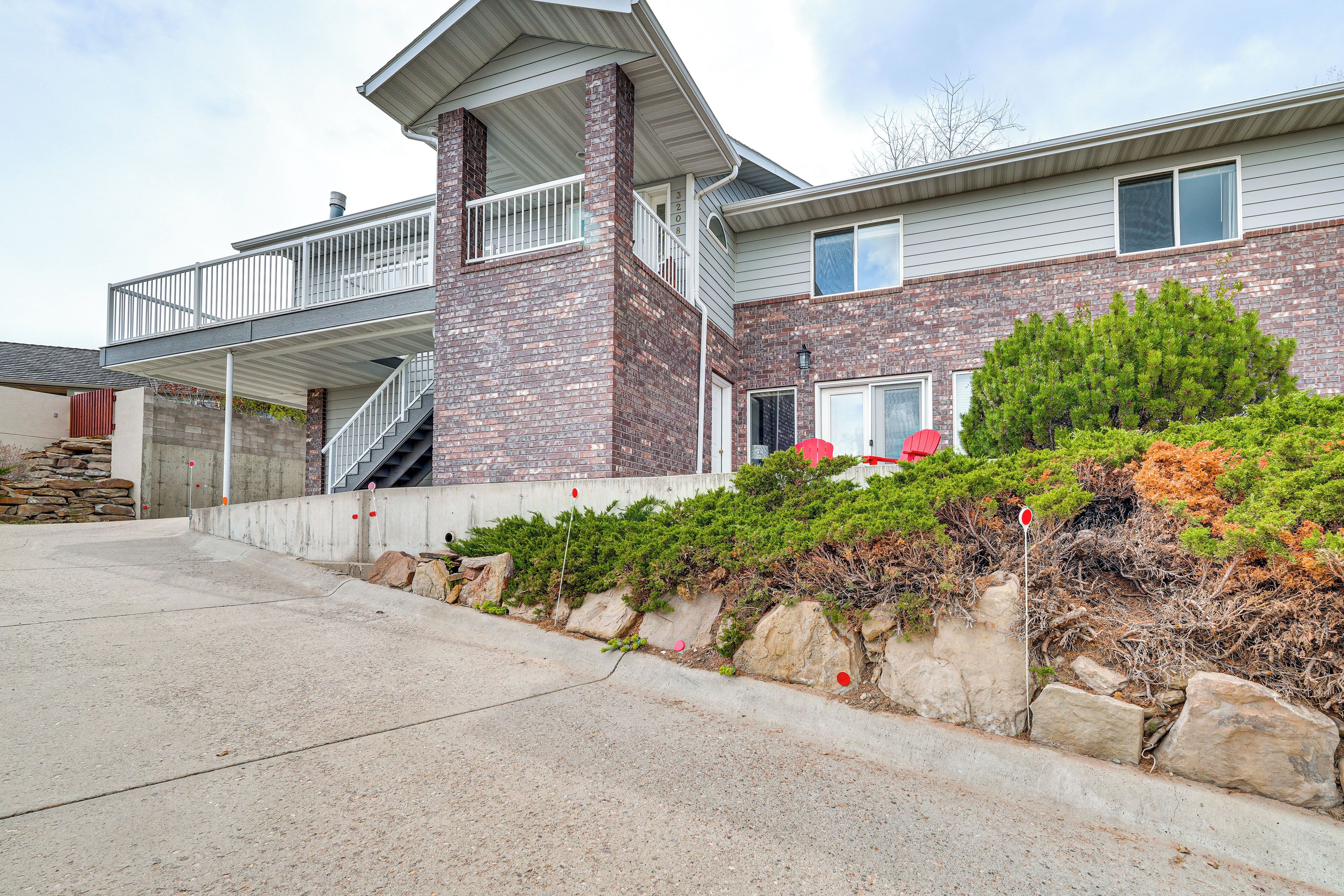 A two-story house with a balcony, a stone retaining wall, and a well-maintained garden.