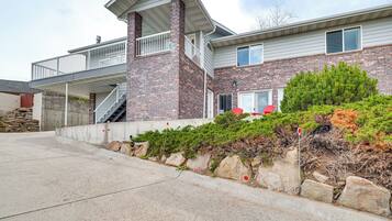 A two-story house with a balcony, a stone retaining wall, and a well-maintained garden.