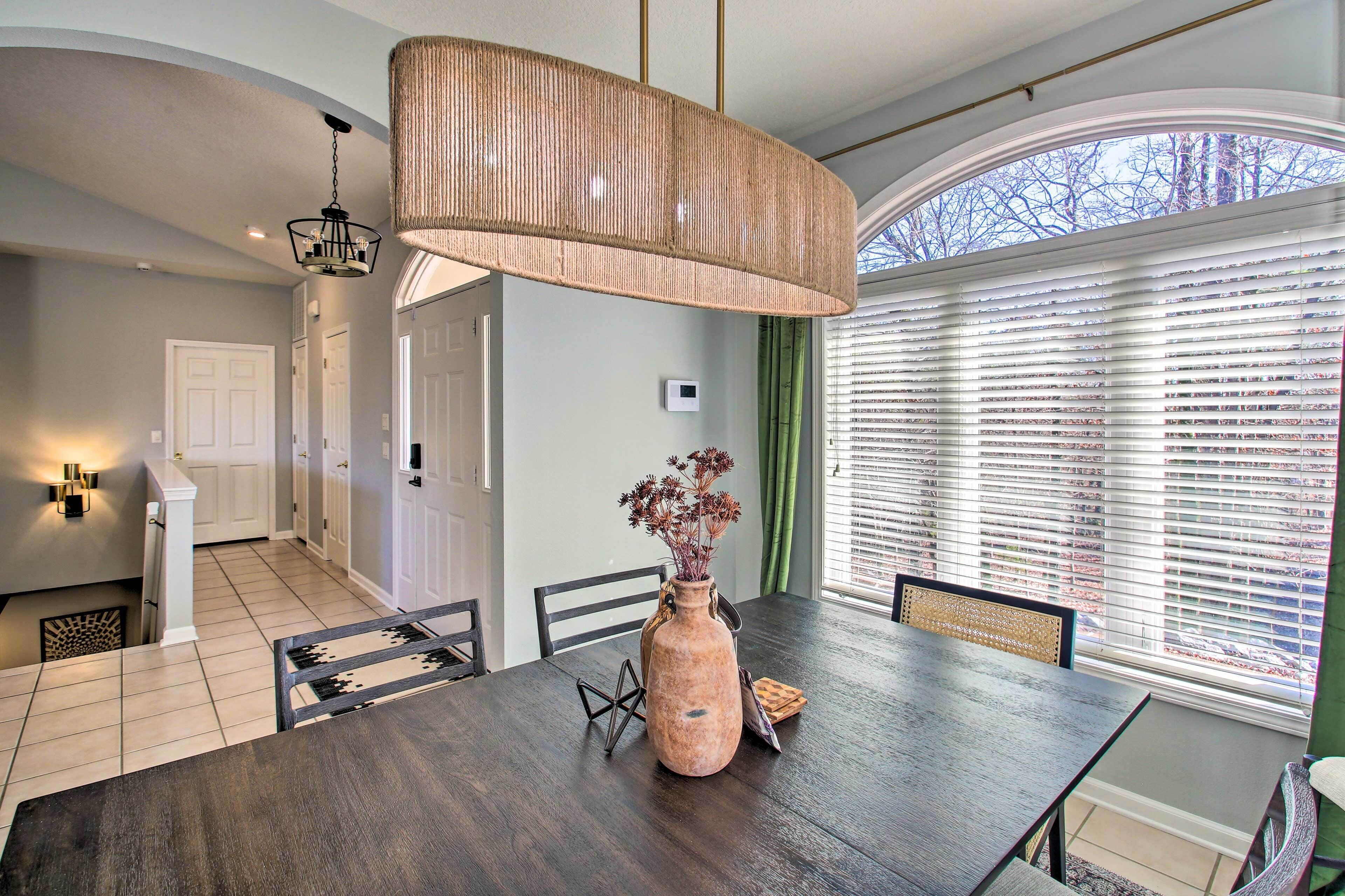 Un coin repas avec une table en bois foncé, un vase rempli de fleurs et un luminaire suspendu.