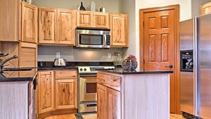 A kitchen with wooden cabinets, a stainless steel microwave, a stove, and a refrigerator.
