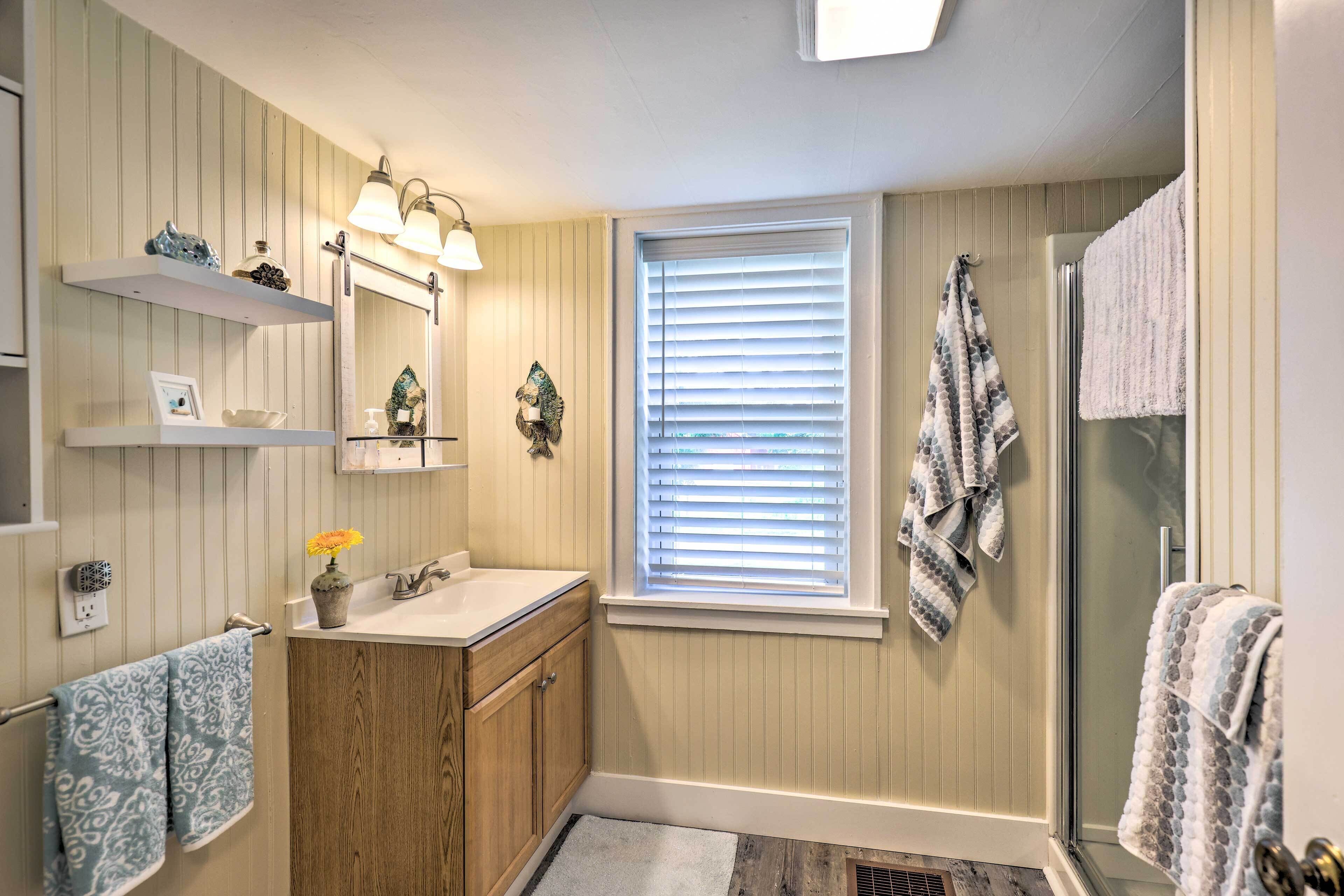 Une salle de bain avec des meubles en bois, un lavabo, un miroir et une douche.