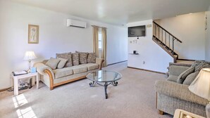 A living room with a sofa, a glass coffee table, a lamp, and a TV mounted on the wall. - 2 Mi to Dtwn Allentown Shops & Eats! Cozy Home (Allentown)