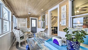 A cozy room with a wooden ceiling, wicker furniture, a blue sofa, and a potted plant.
