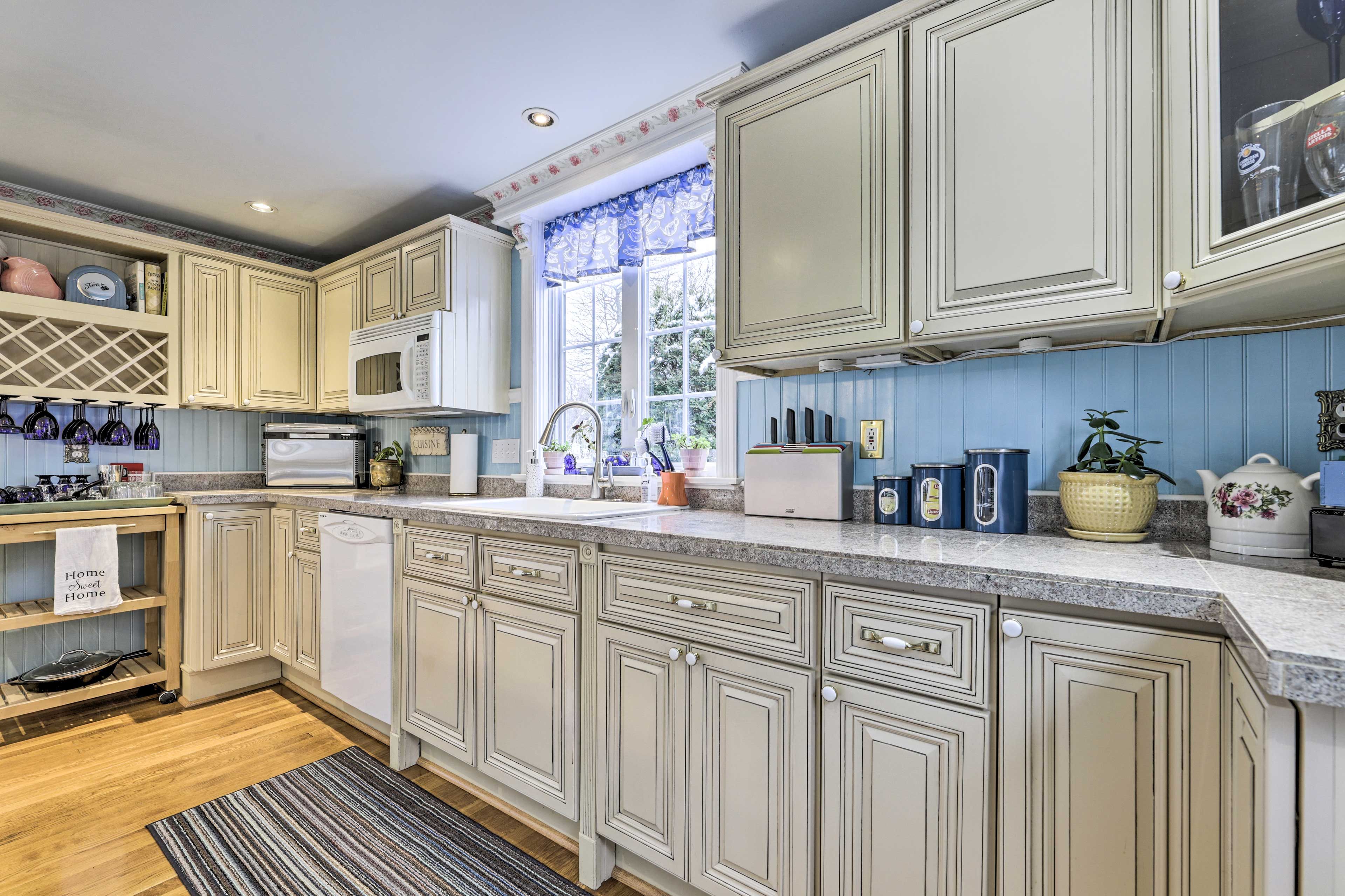 A kitchen with light-colored cabinetry, a microwave, a sink, and various kitchen appliances.