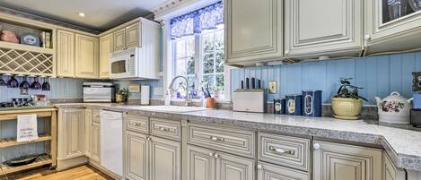 A kitchen with light-colored cabinetry, a microwave, a sink, and various kitchen appliances.
