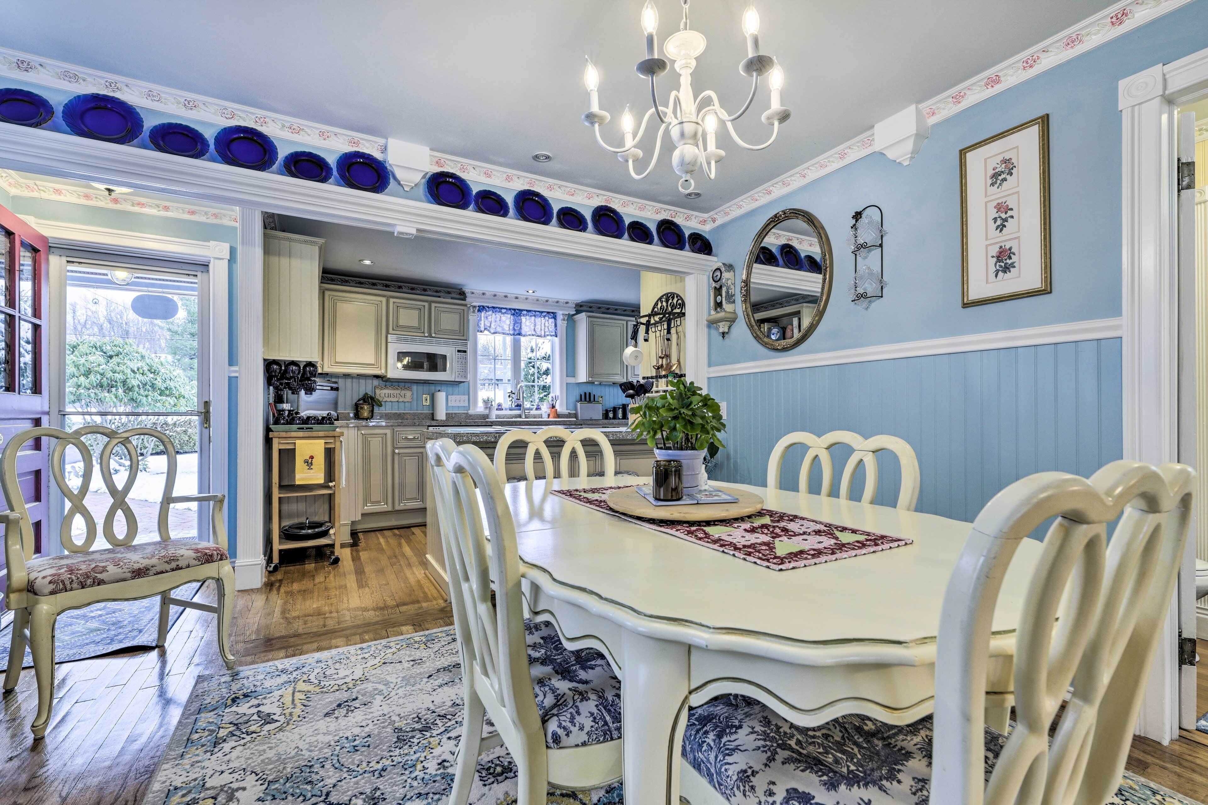 A dining area with a white table, chairs, and a chandelier.