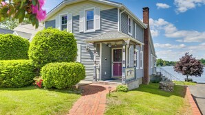 A two-story house with a front porch, a brick pathway leading to the entrance, and a view of a lake. - Lakefront Home, Close to Mt Southington! (Wolcott)