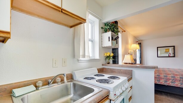 A compact kitchen with a sink, stove, and cabinets.