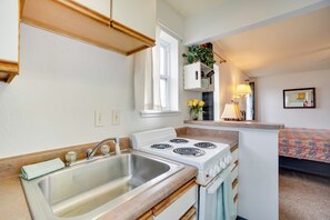 A compact kitchen with a sink, stove, and cabinets. - Loveland Vacation Rental Near Downtown! (Loveland)