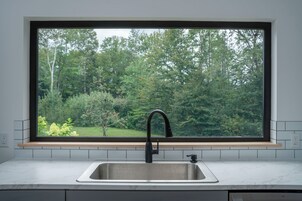 Una cocina con un amplio ventanal, un lavamanos y un grifo.