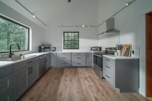 Una cocina moderna con gabinetes grises, piso de madera, un ventanal grande y un microondas.