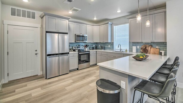 A modern kitchen with stainless steel appliances, white cabinetry, and a central island with bar stools.