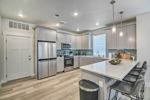 A modern kitchen with stainless steel appliances, white cabinetry, and a central island with bar stools. - Gorgeous Greeley Getaway - Close to Parks! (Greeley)
