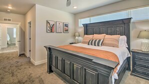 A bedroom with a dark wooden bed, a ceiling fan, and a window with blinds.